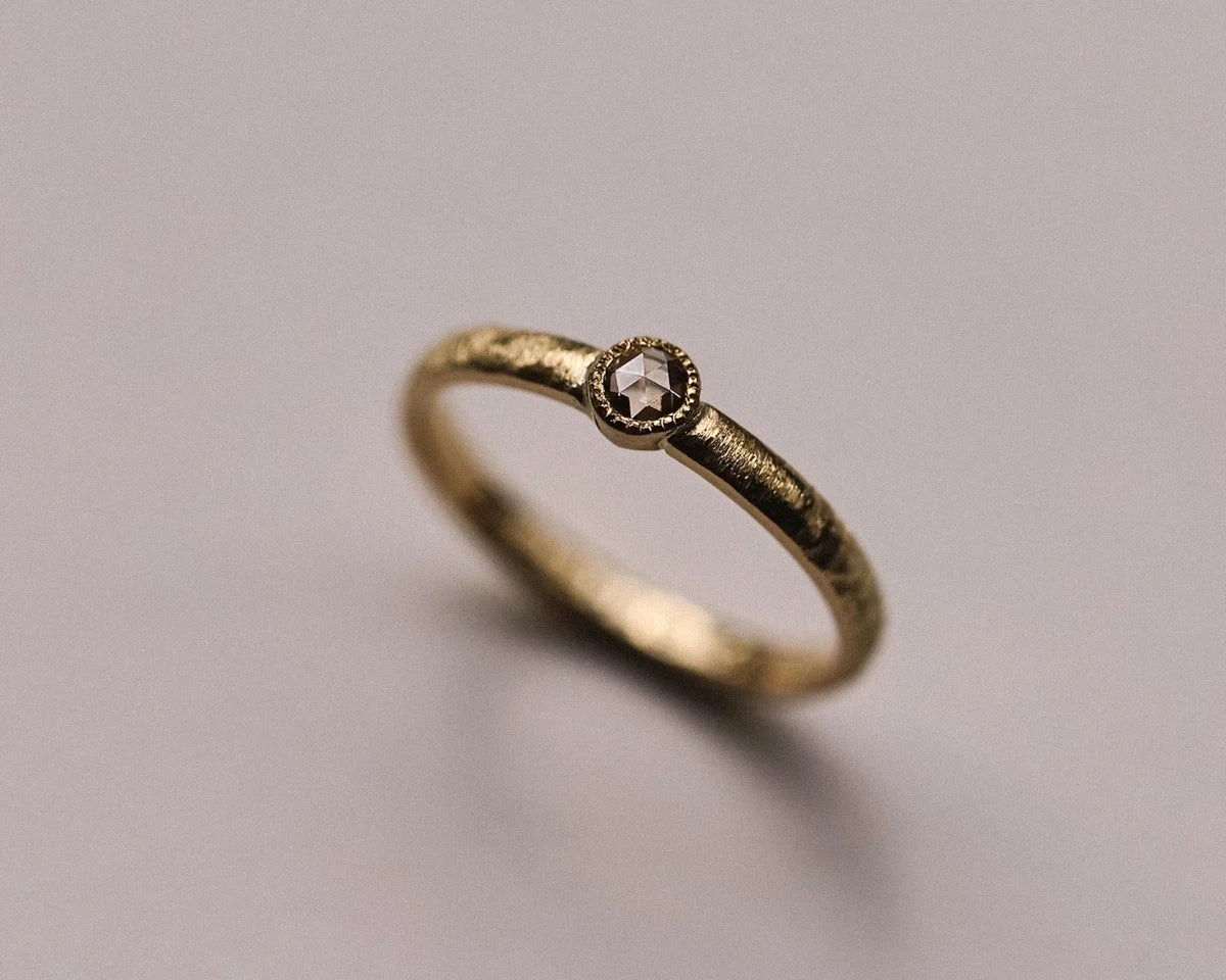 Angled view of 18ct yellow gold horn texture ring with champagne diamond