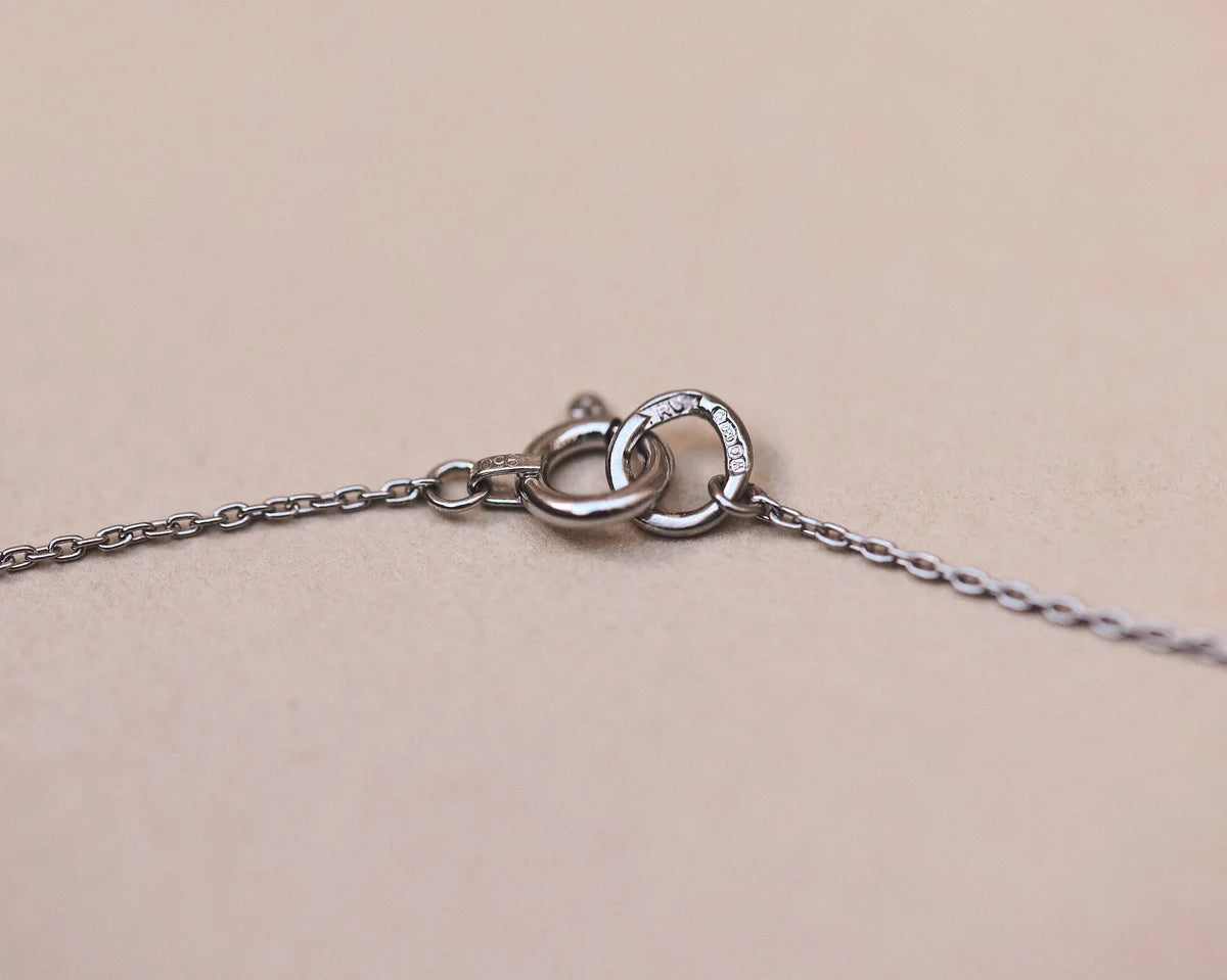 Close-up of a silver necklace with a clasp on a beige background