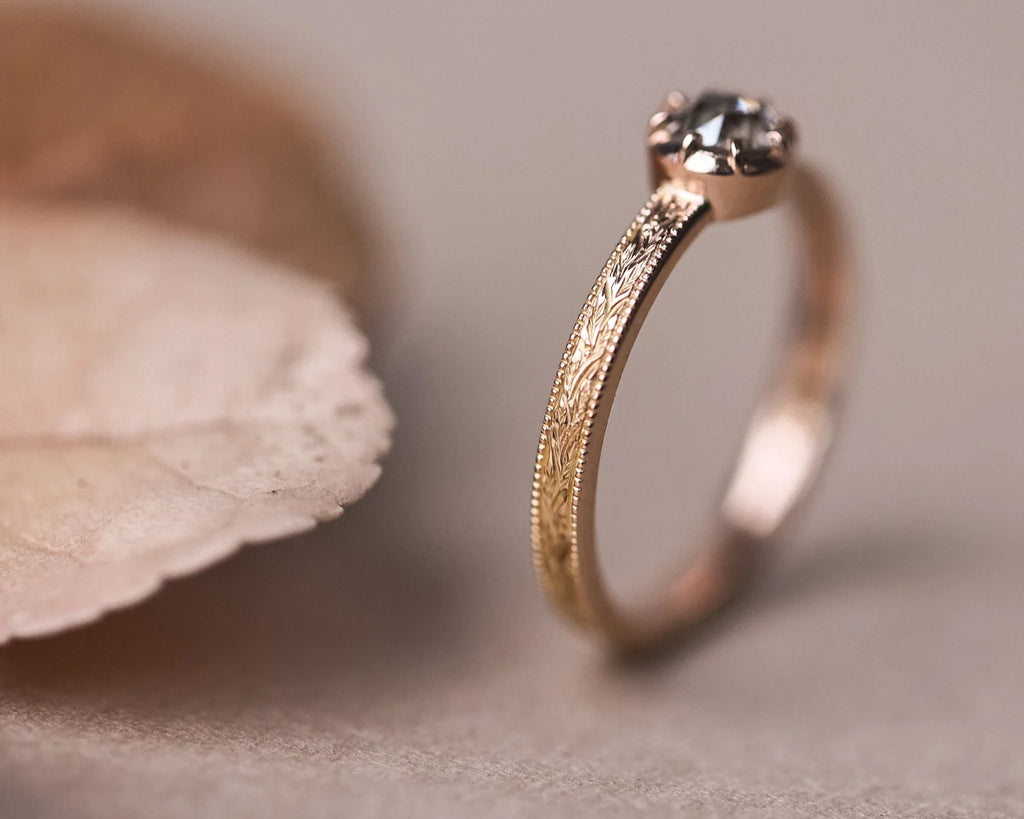 Portrait view of brown-grey diamond ring with engraved rose gold band