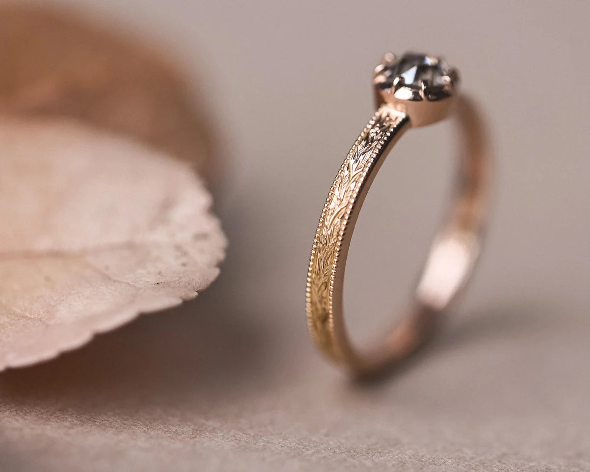 Portrait view of brown-grey diamond ring with engraved rose gold band