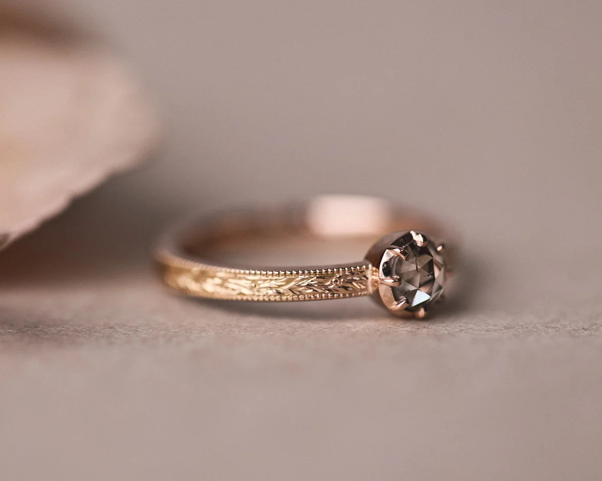 Close-up of brown-grey rose-cut diamond ring with laurel engraved band