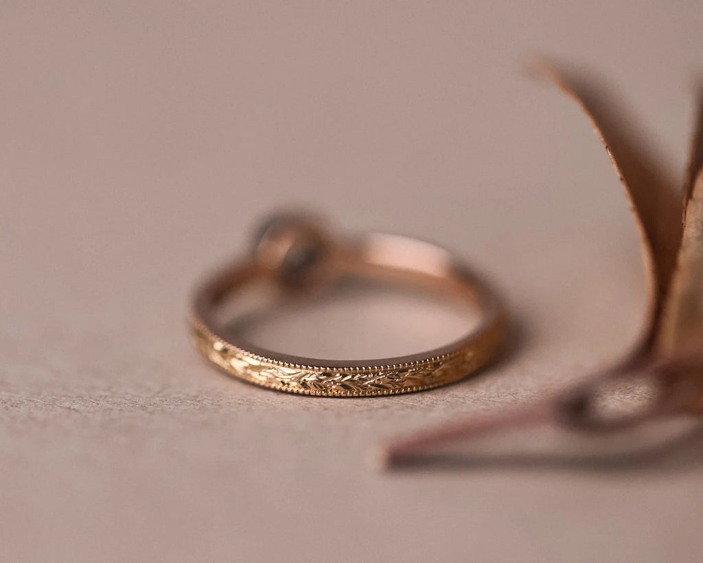 Rear profile of rose gold laurel engraved ring with brown-grey diamond