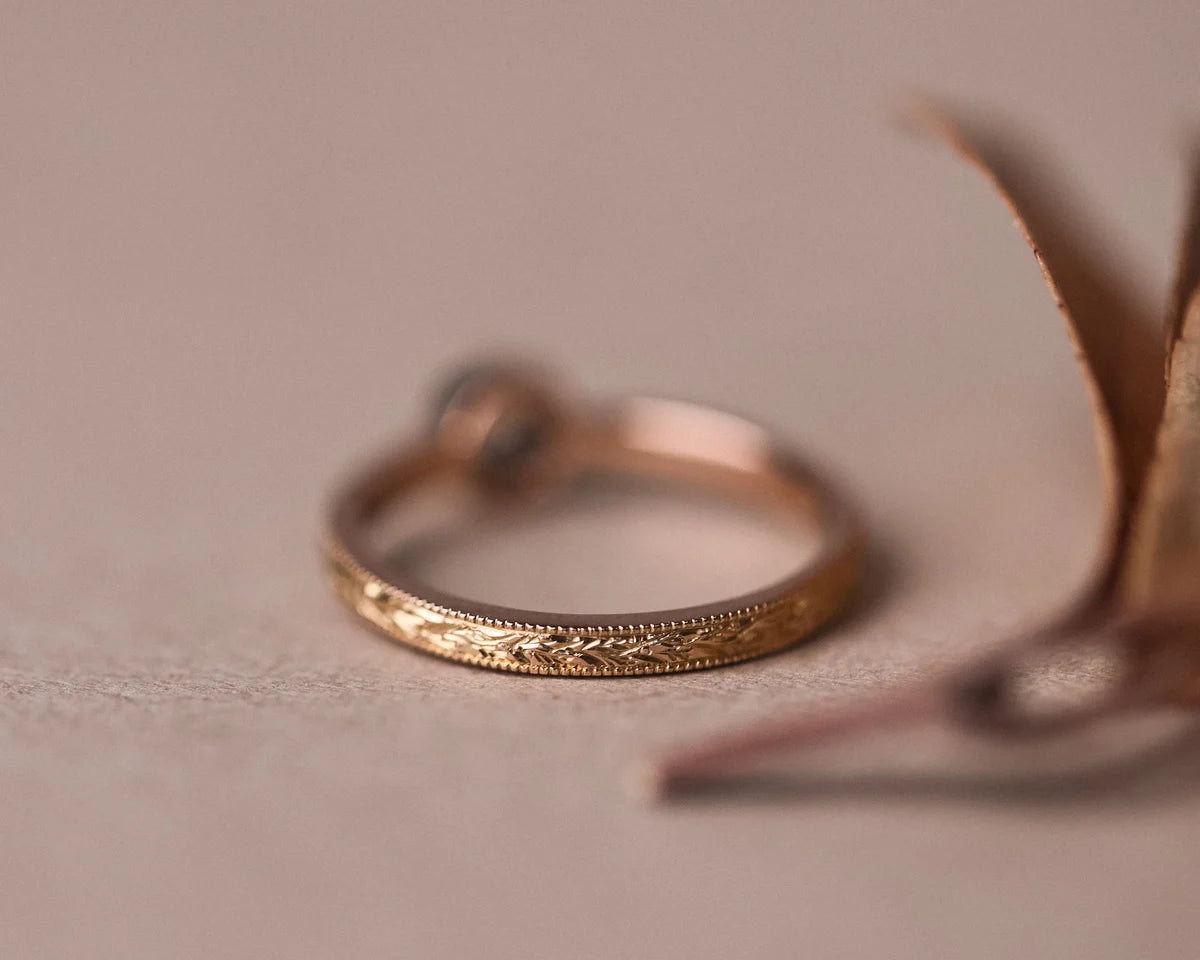Rear profile of rose gold laurel engraved ring with brown-grey diamond