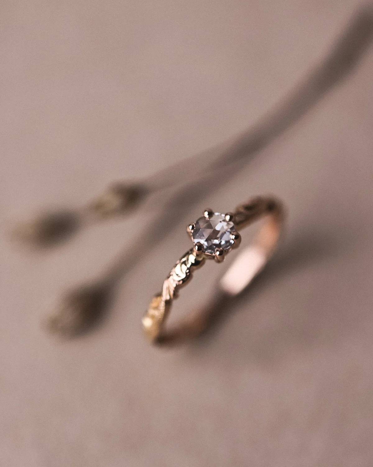 Angled close-up of handmade floral carved diamond ring in rose gold