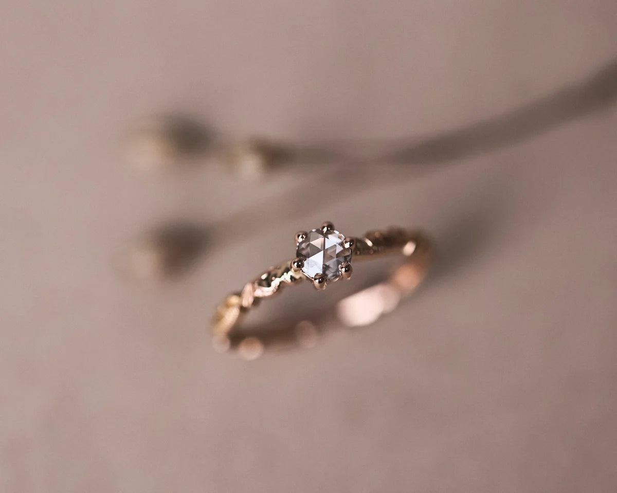 Soft focus view of rose-cut diamond floral ring in rose gold