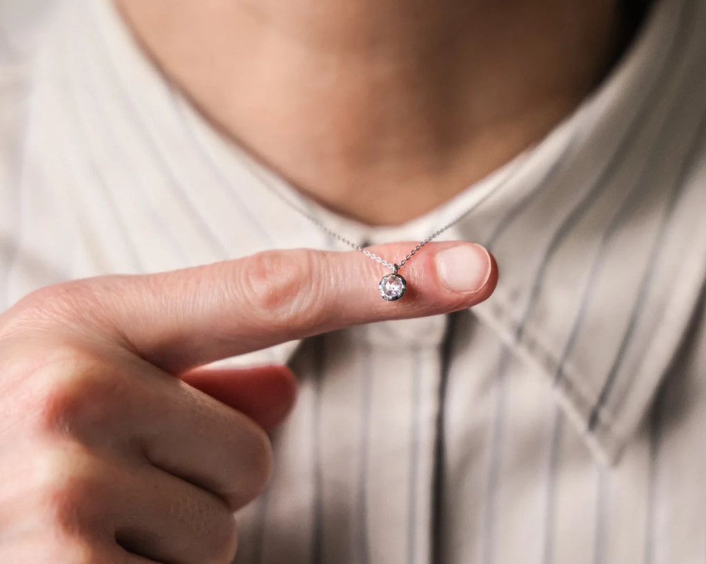Person holding a diamond necklace close to the camera