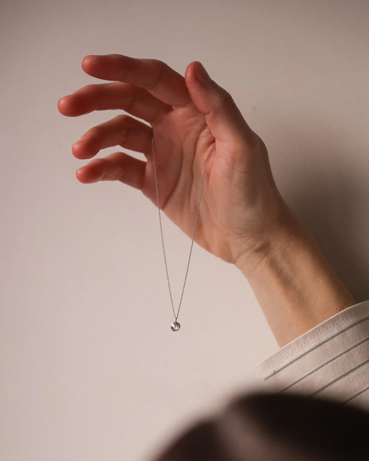 Hand holding a necklace against a plain background
