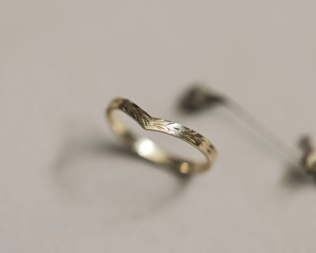Detailed view of olive leaf engraving on yellow gold wishbone band