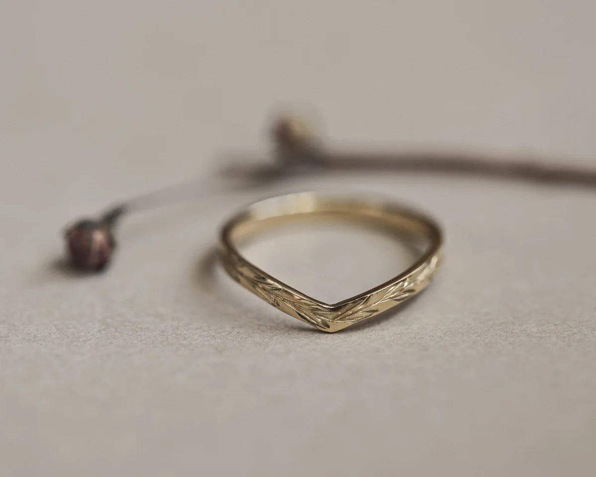 Soft focus view of 2mm olive leaf wishbone ring in yellow gold