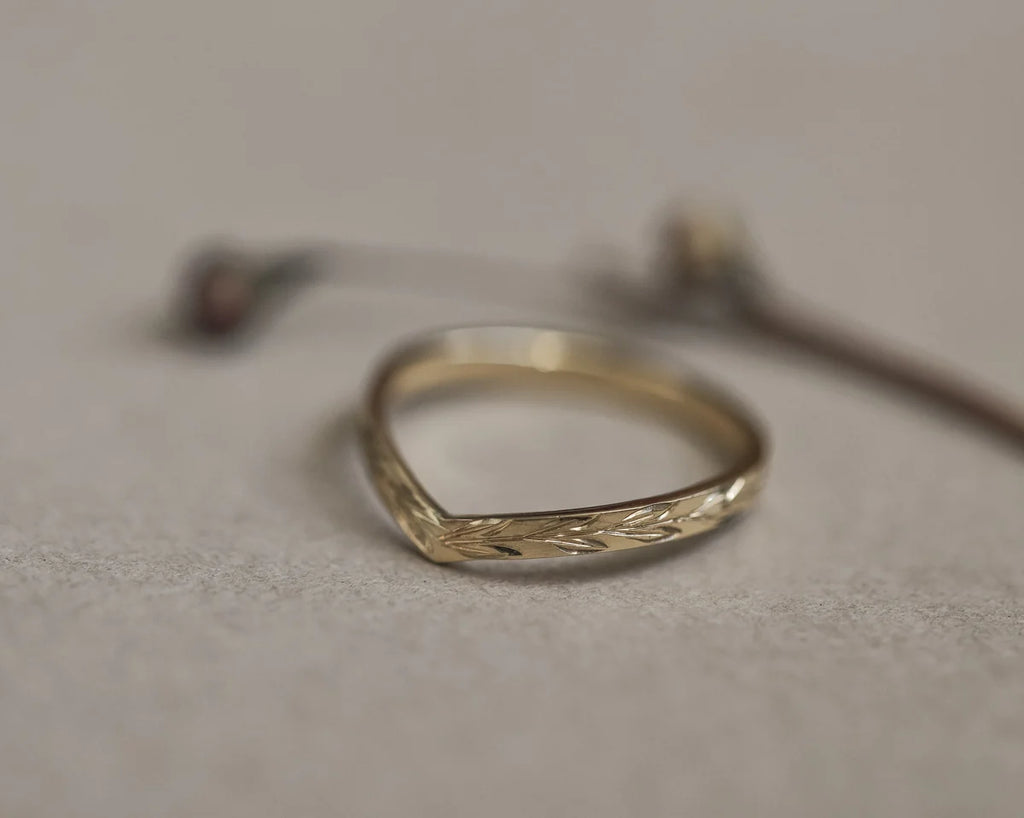 Angled view of yellow gold olive leaf engraved wishbone band