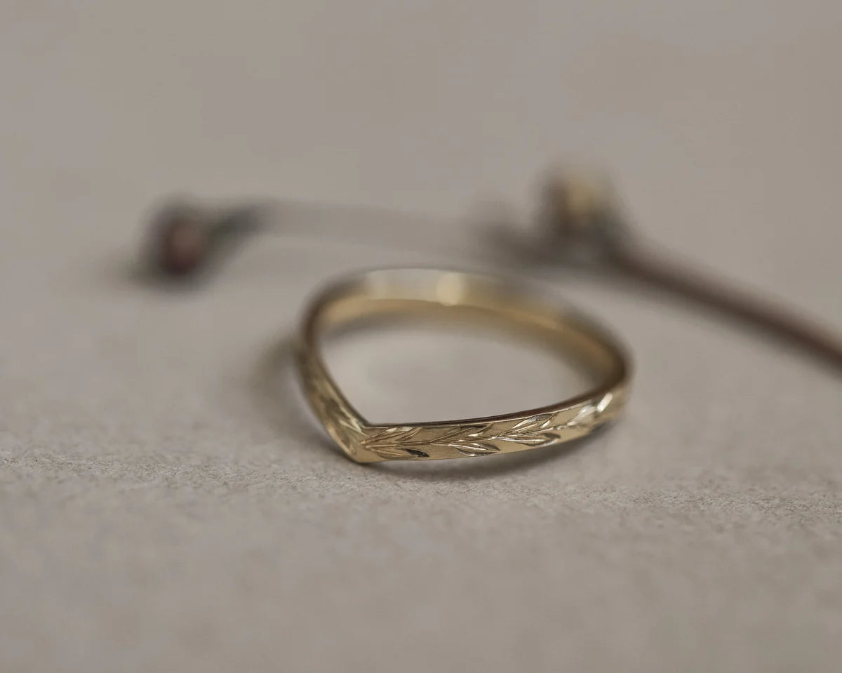 Angled view of yellow gold olive leaf engraved wishbone band