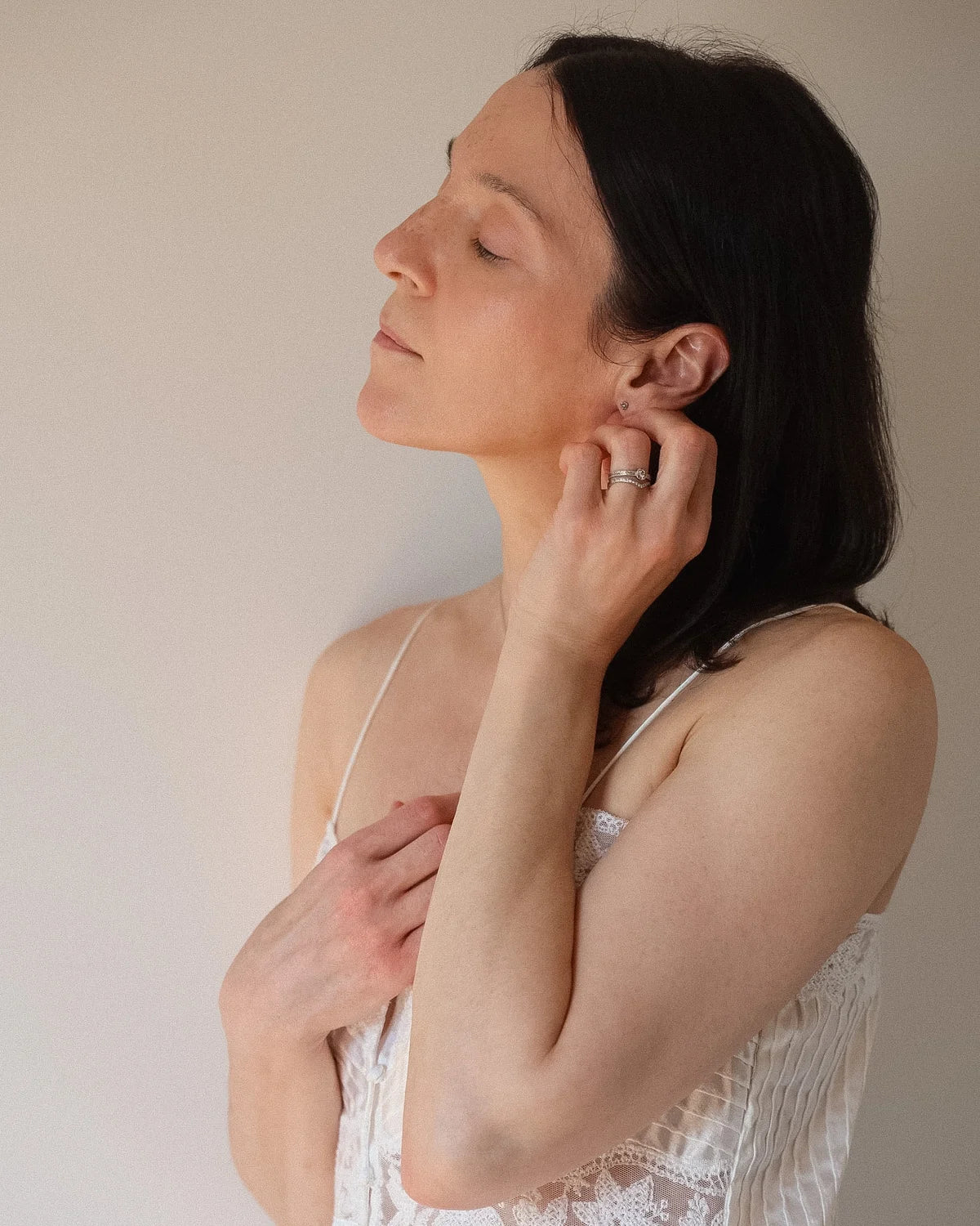 Woman wearing a white lace top against a plain background