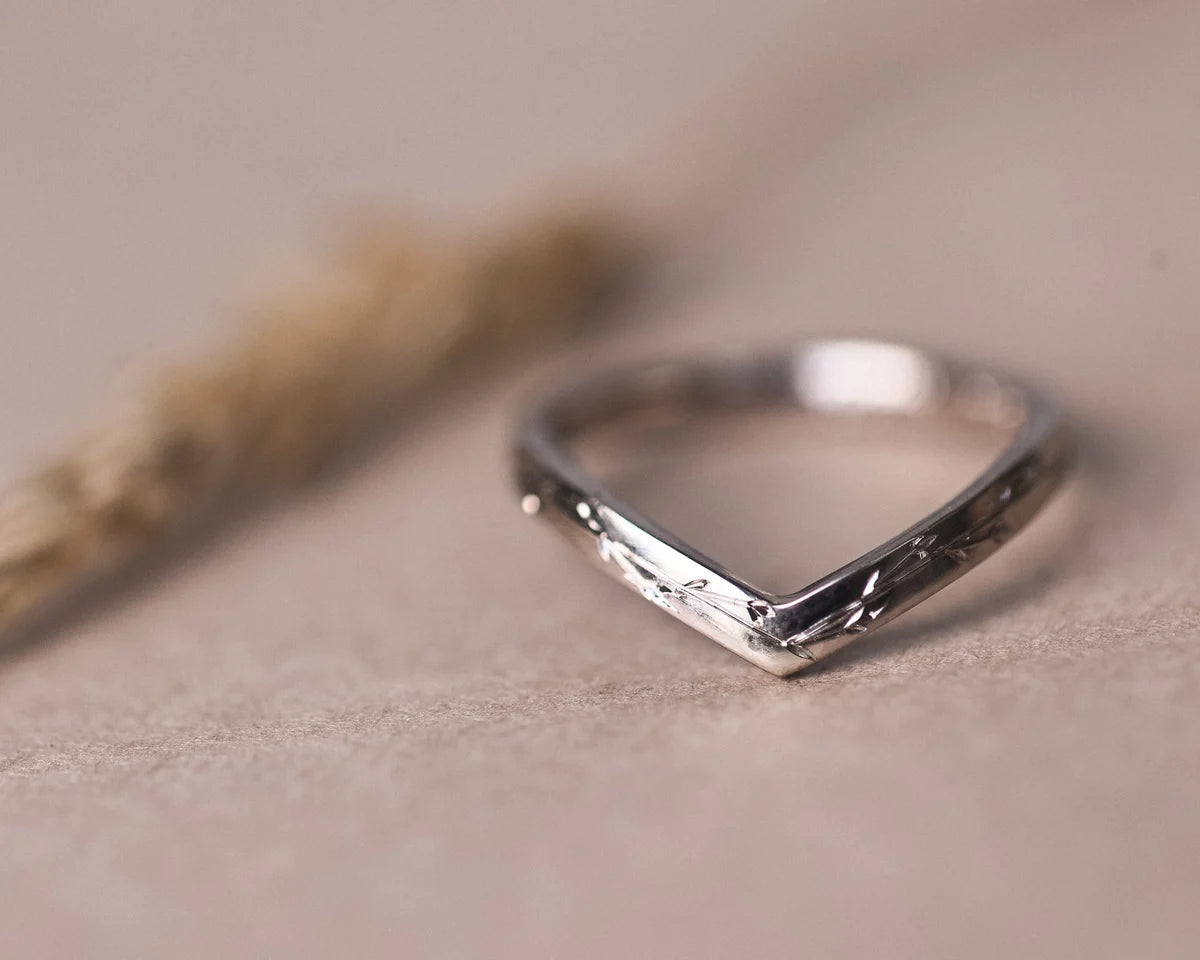 Angled close-up of pressed flower engraved wishbone ring