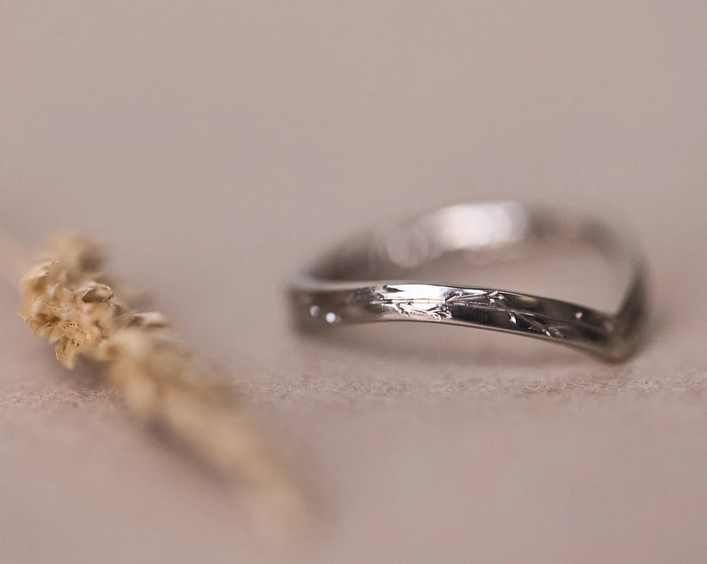 Soft focus view of 18ct white gold pressed flower wishbone ring