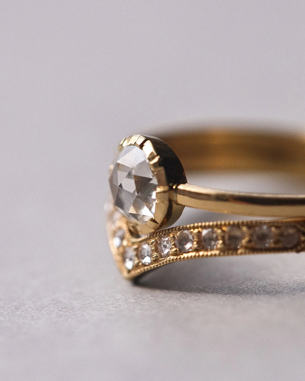 Close-up of rose-cut diamond ring with pavé wishbone wedding band