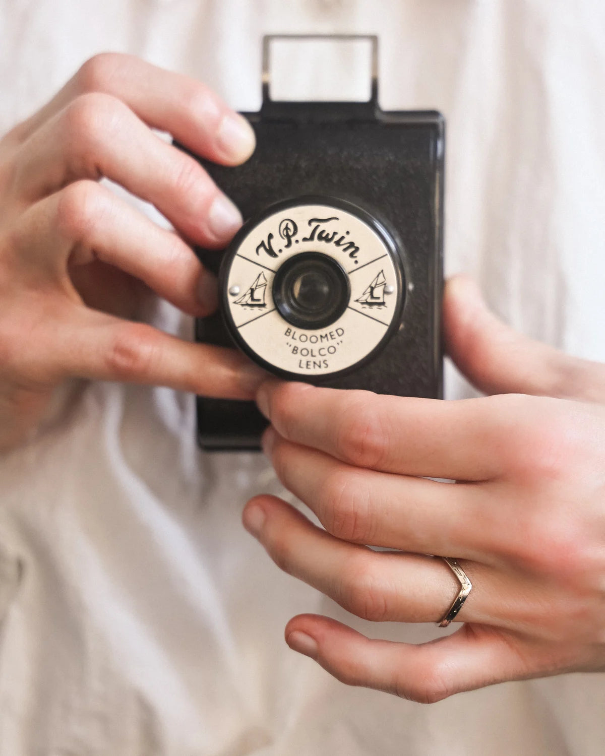 Pressed flower wishbone ring worn while holding vintage camera