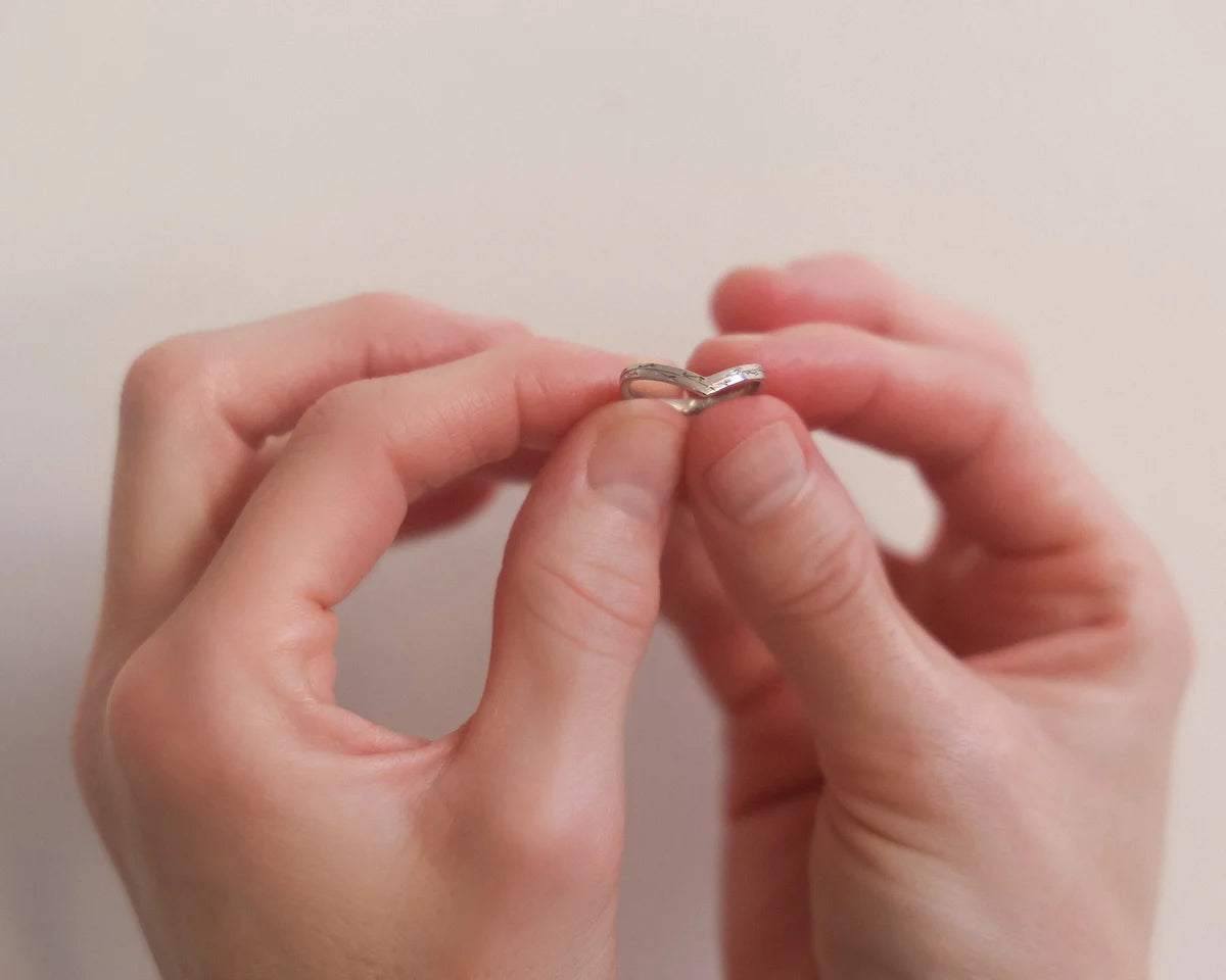 18ct white gold wishbone ring held between fingers