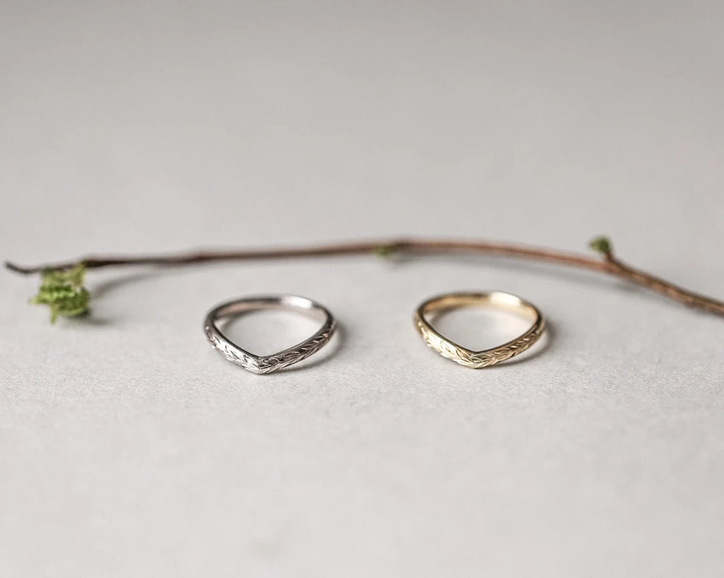 Two silver rings on a light gray surface with a branch in the background