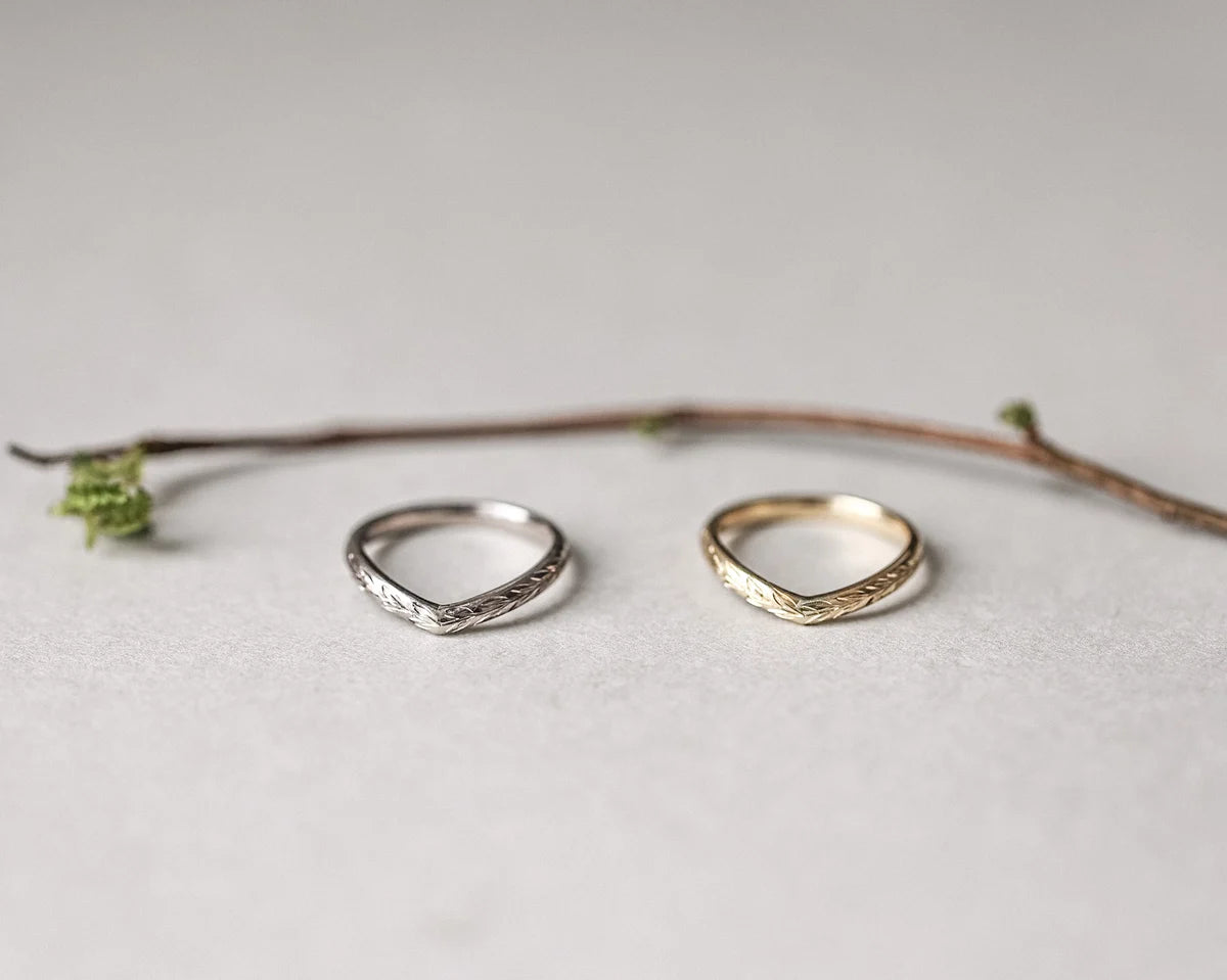 Two silver rings on a light gray surface with a branch in the background