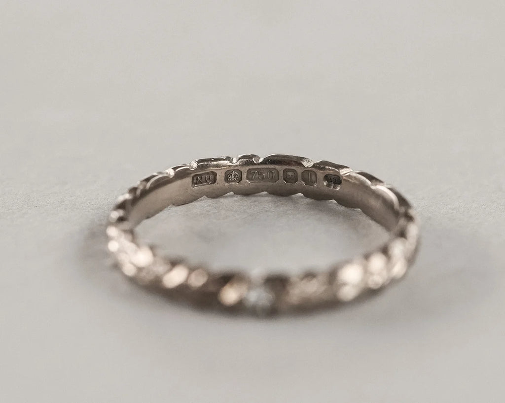 Silver ring with engraved details on a light gray background