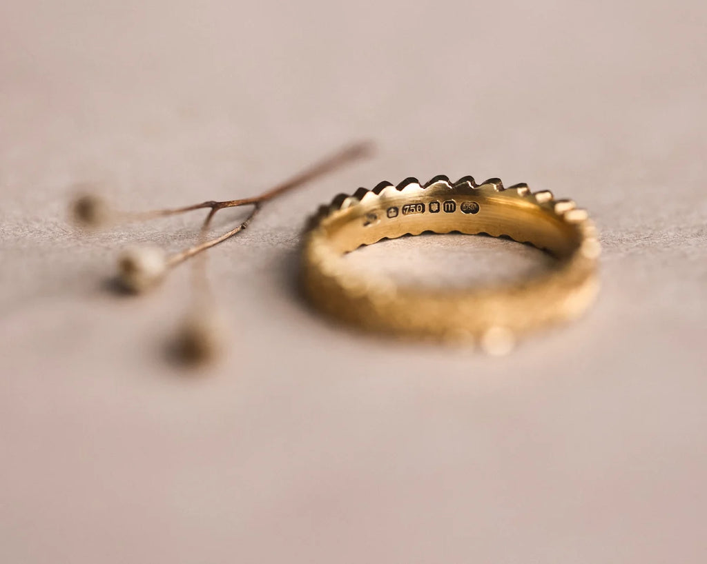 Gold ring with engraved text on a soft beige background