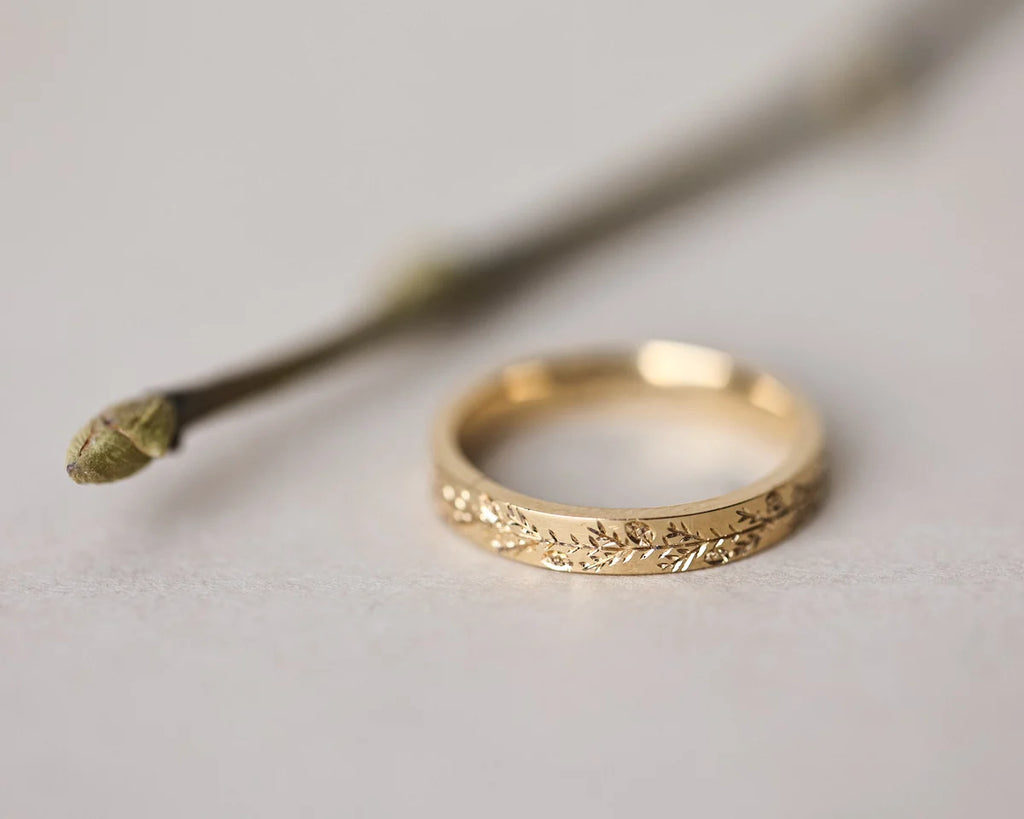 Gold ring with intricate design on a light gray background