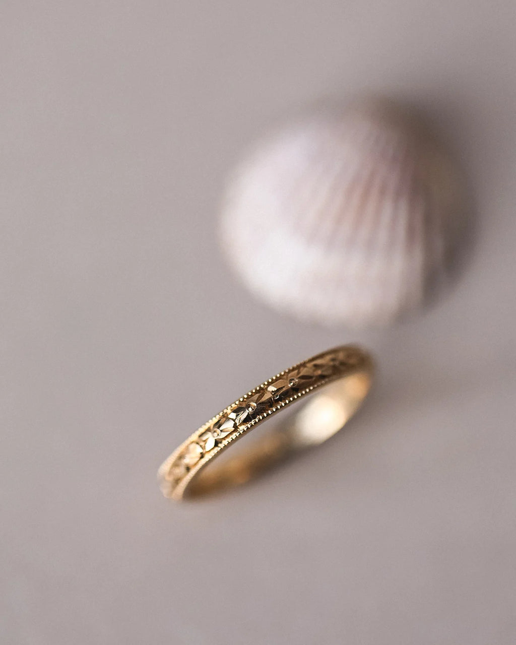 Gold ring with intricate design on a gray background