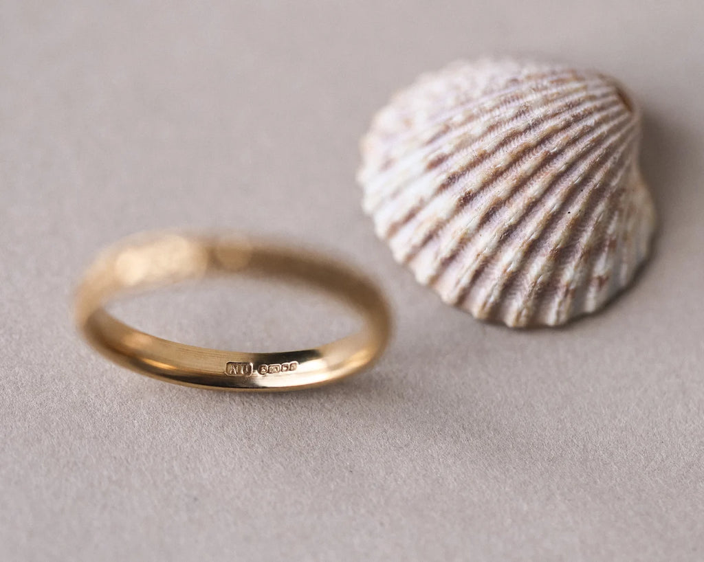 Gold ring and shell on a neutral background