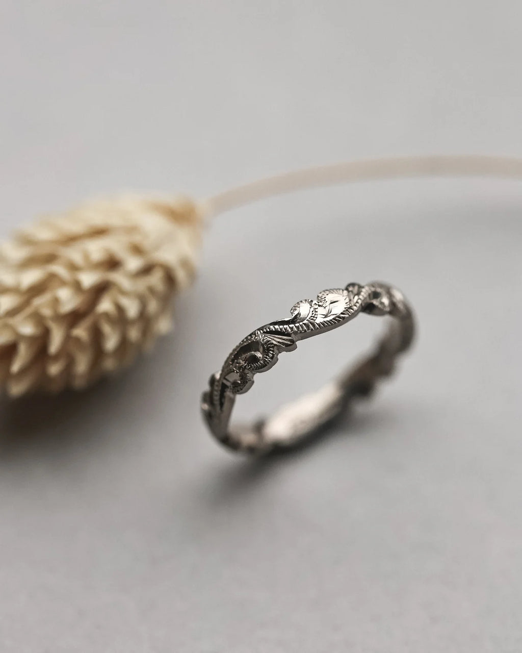 Silver ring with intricate design on a light gray background