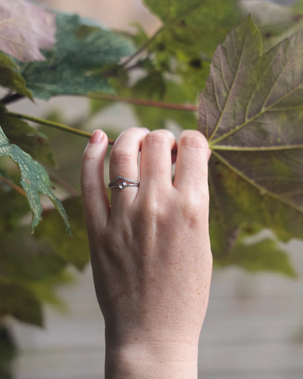 Platinum rose-cut diamond ring worn on hand with green leaf