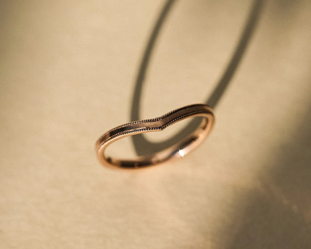 Side profile of handmade rose gold wishbone ring with milled edge