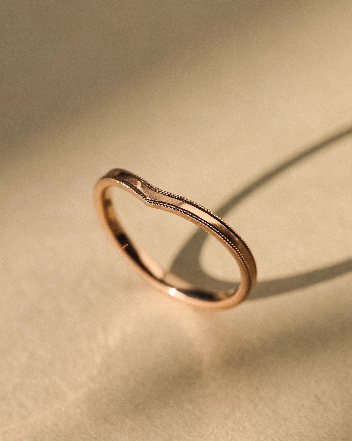 Vertical view of 18ct rose gold milled edge wishbone ring