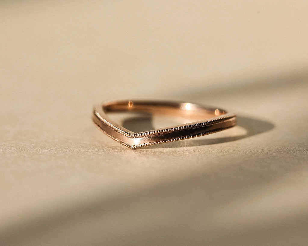 Low profile view of 2mm milled edge wishbone ring in rose gold