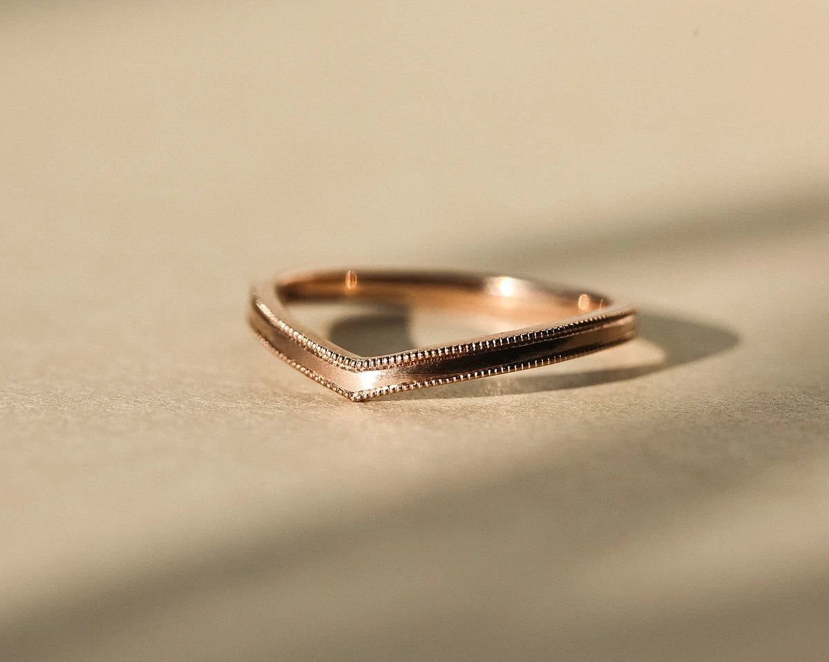 Low profile view of 2mm milled edge wishbone ring in rose gold