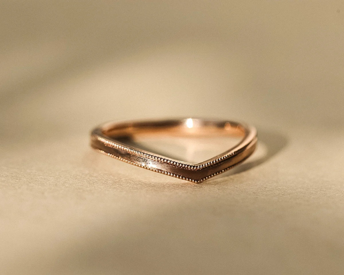 Front view of 18ct rose gold wishbone ring with hand engraved milled edge