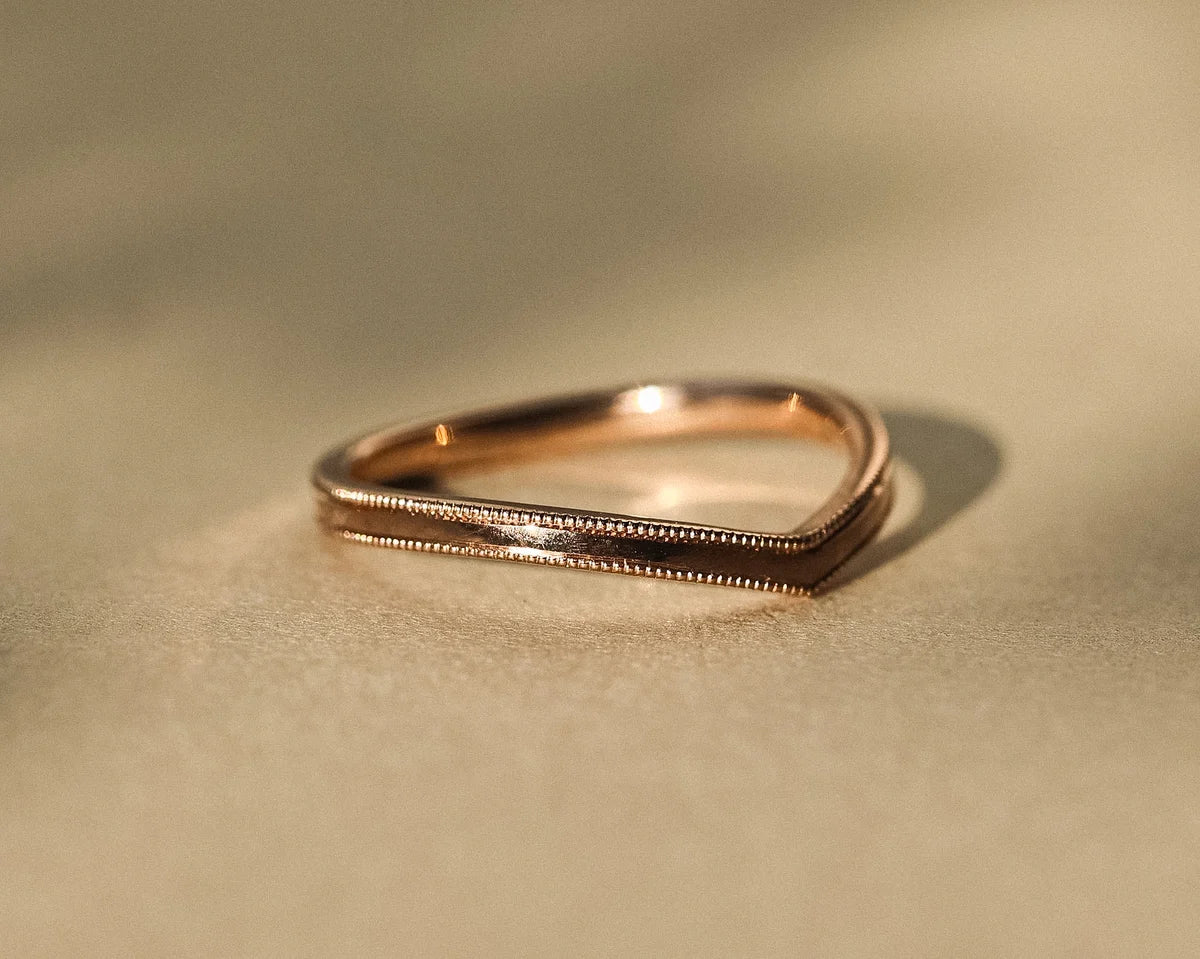 Soft light close-up of V-shaped rose gold wedding ring