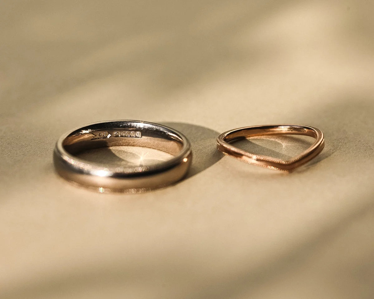 Rose gold wishbone wedding ring shown beside platinum band