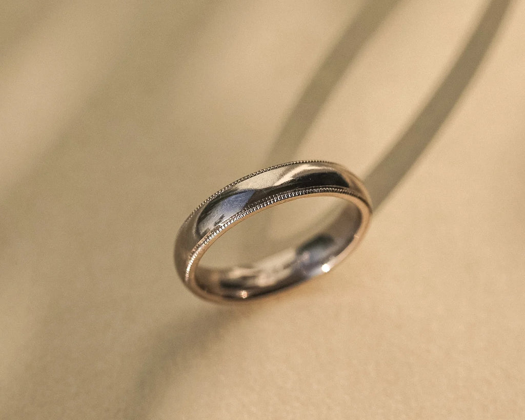 Close-up of 18ct white gold milled edge wedding ring on soft fabric