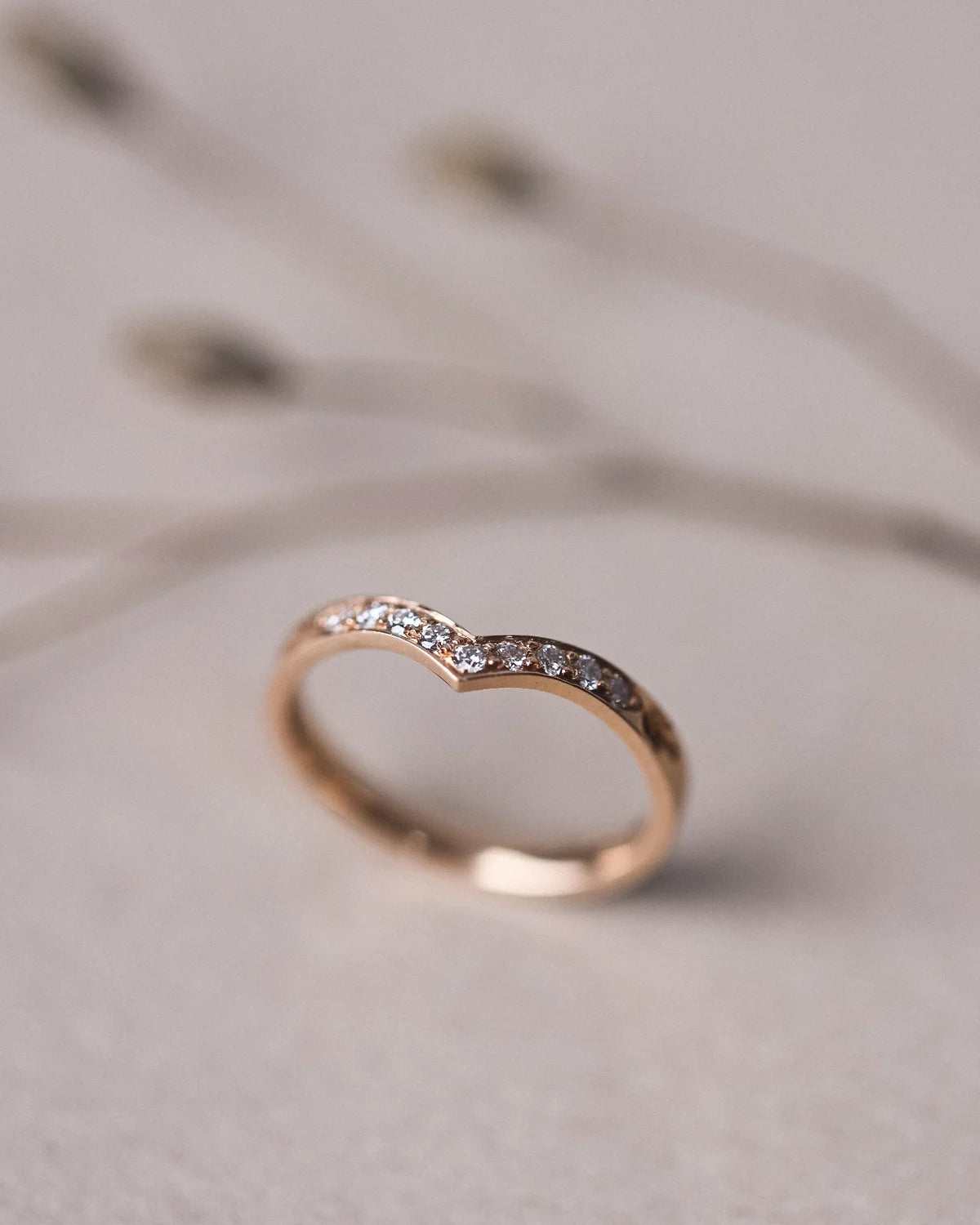 Rose gold ring with small diamonds on a light background