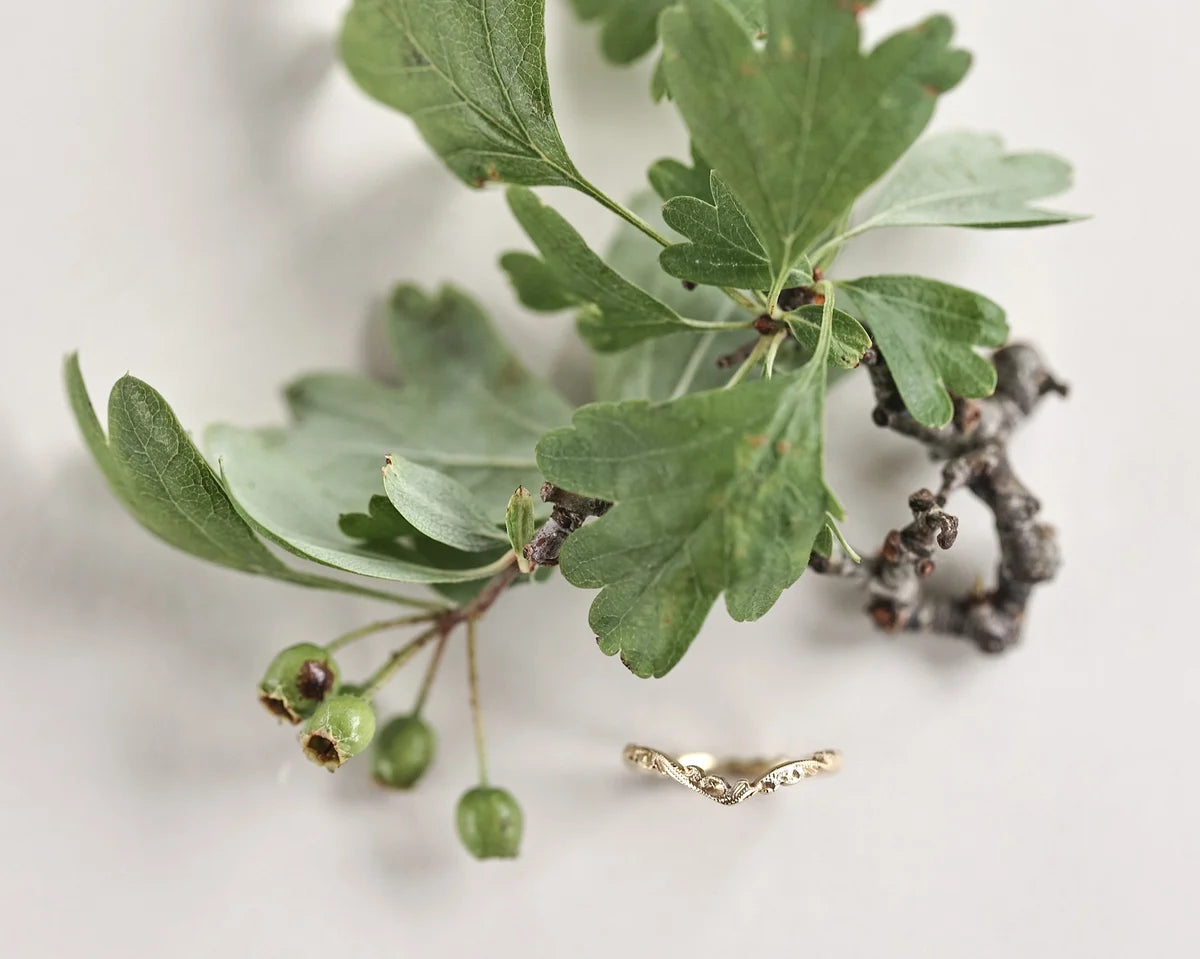 Gold ring on a branch with green leaves and berries