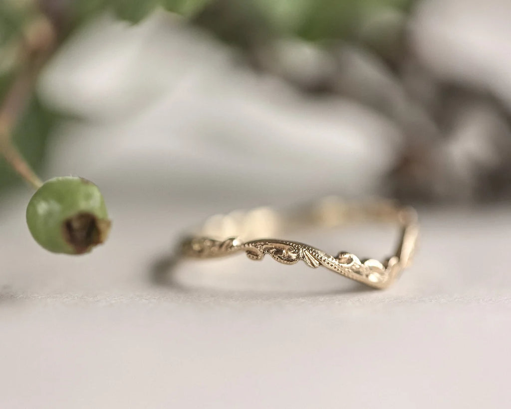 Gold ring with intricate design on a light background