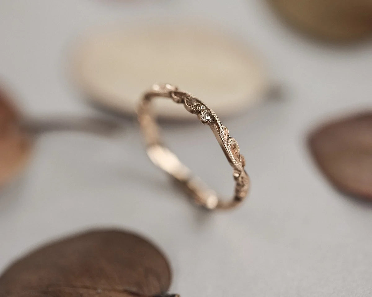 Rose gold ring with intricate design on a neutral background