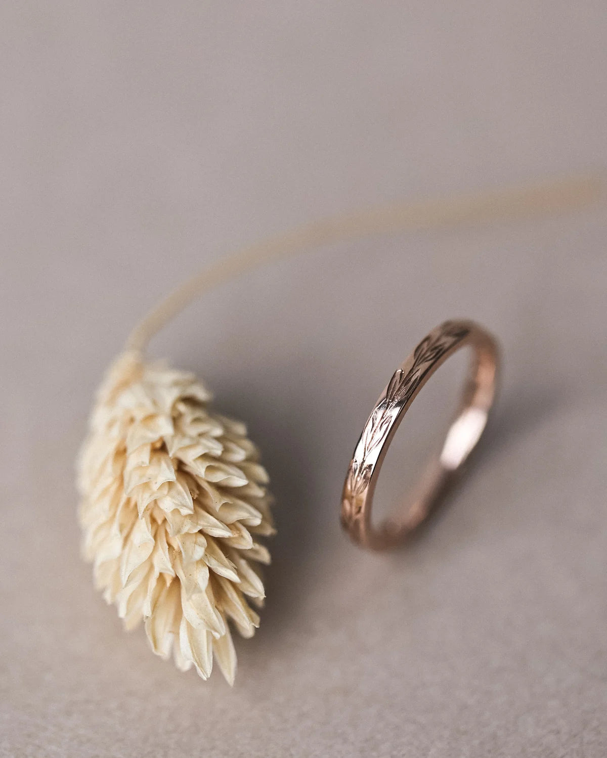 Vertical view of rose gold olive leaf wedding ring with botanical styling