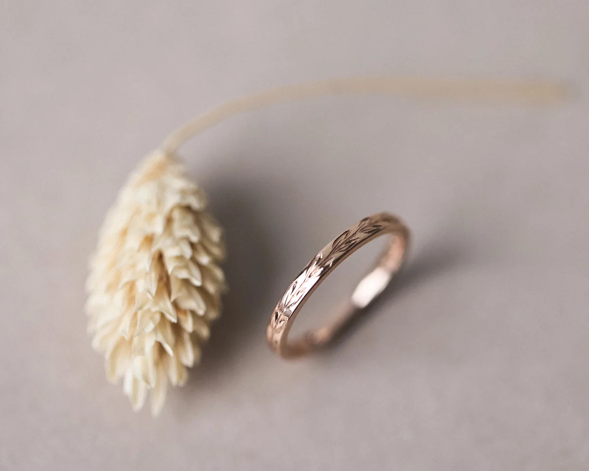 Angled view of 18ct rose gold olive leaf engraved wedding ring