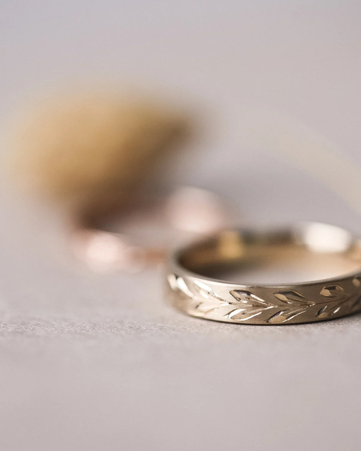 Close-up of matte olive leaf engraved wedding ring in yellow gold
