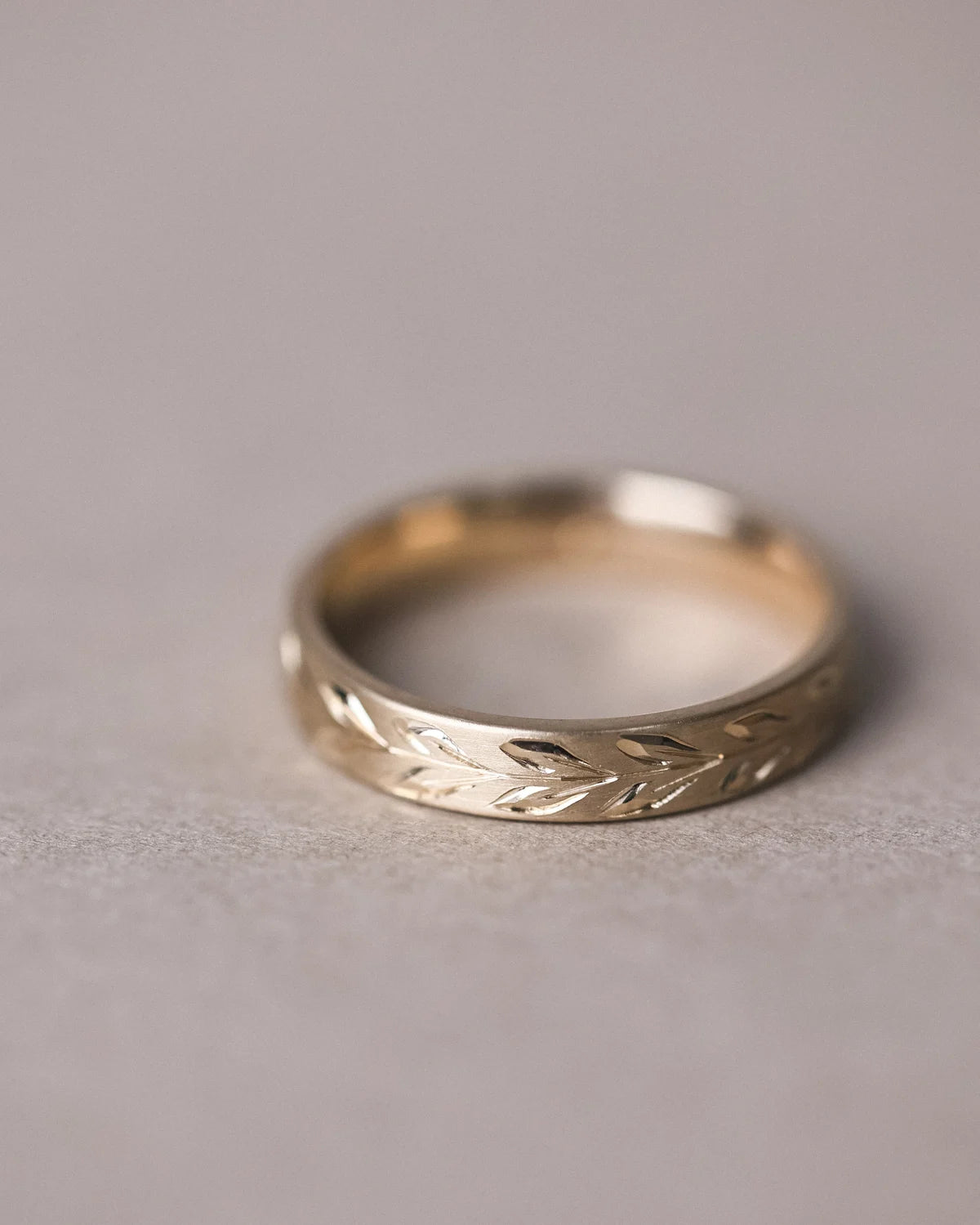 Front view of 4mm flat court wedding ring with olive leaf engraving