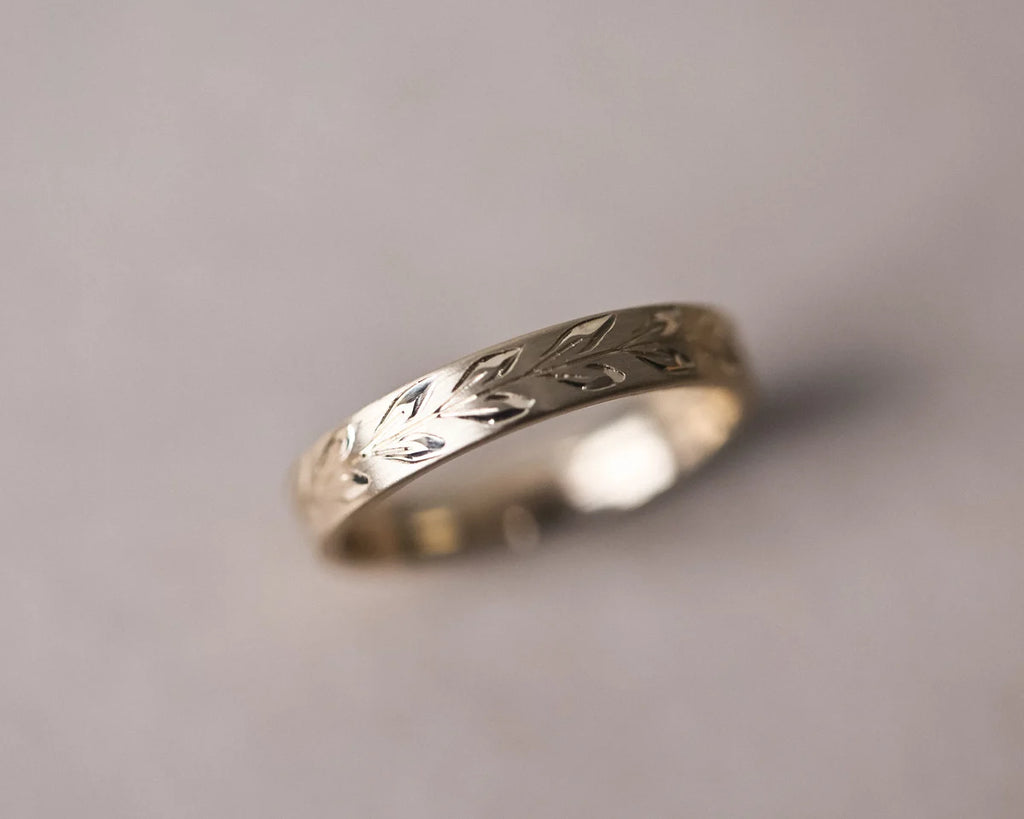 Detailed view of olive leaf engraving on matte 9ct yellow gold band