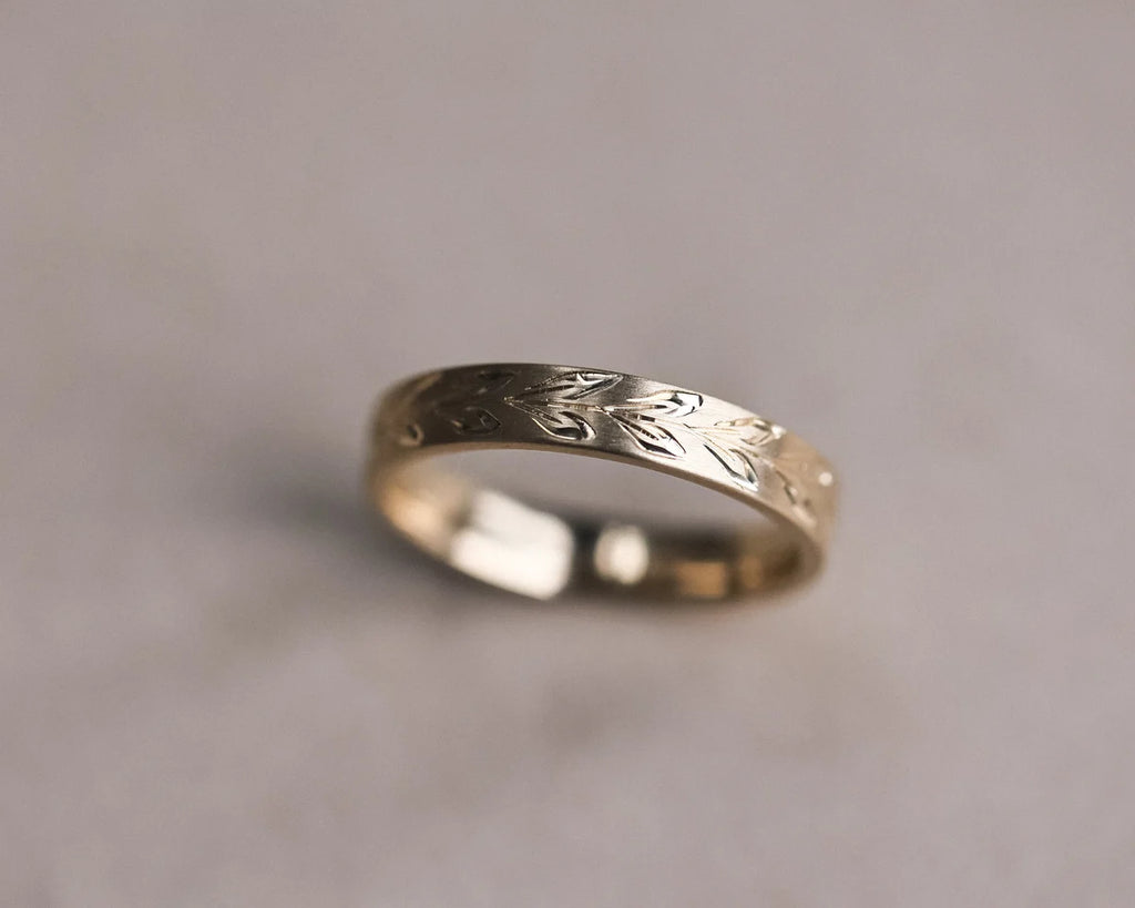 Low angle view of olive leaf engraved wedding ring in 9ct yellow gold