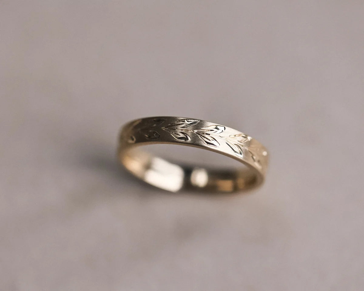 Low angle view of olive leaf engraved wedding ring in 9ct yellow gold