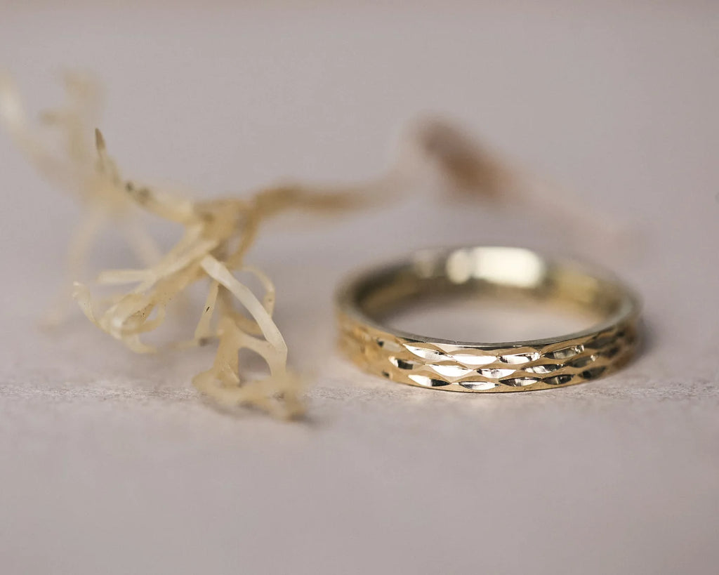 Gold ring with textured band on a light background